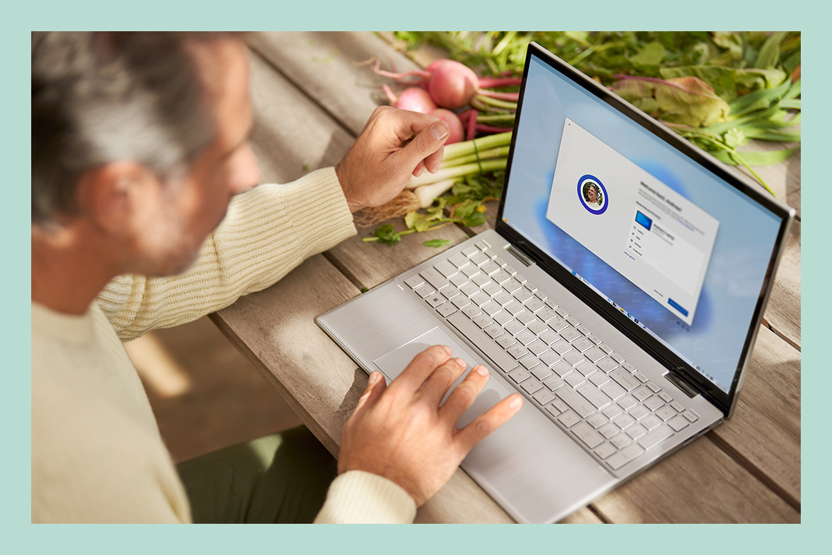En man använder en laptop och installerar befintliga filer, appar och standardkonfigurationer via Windows 11.